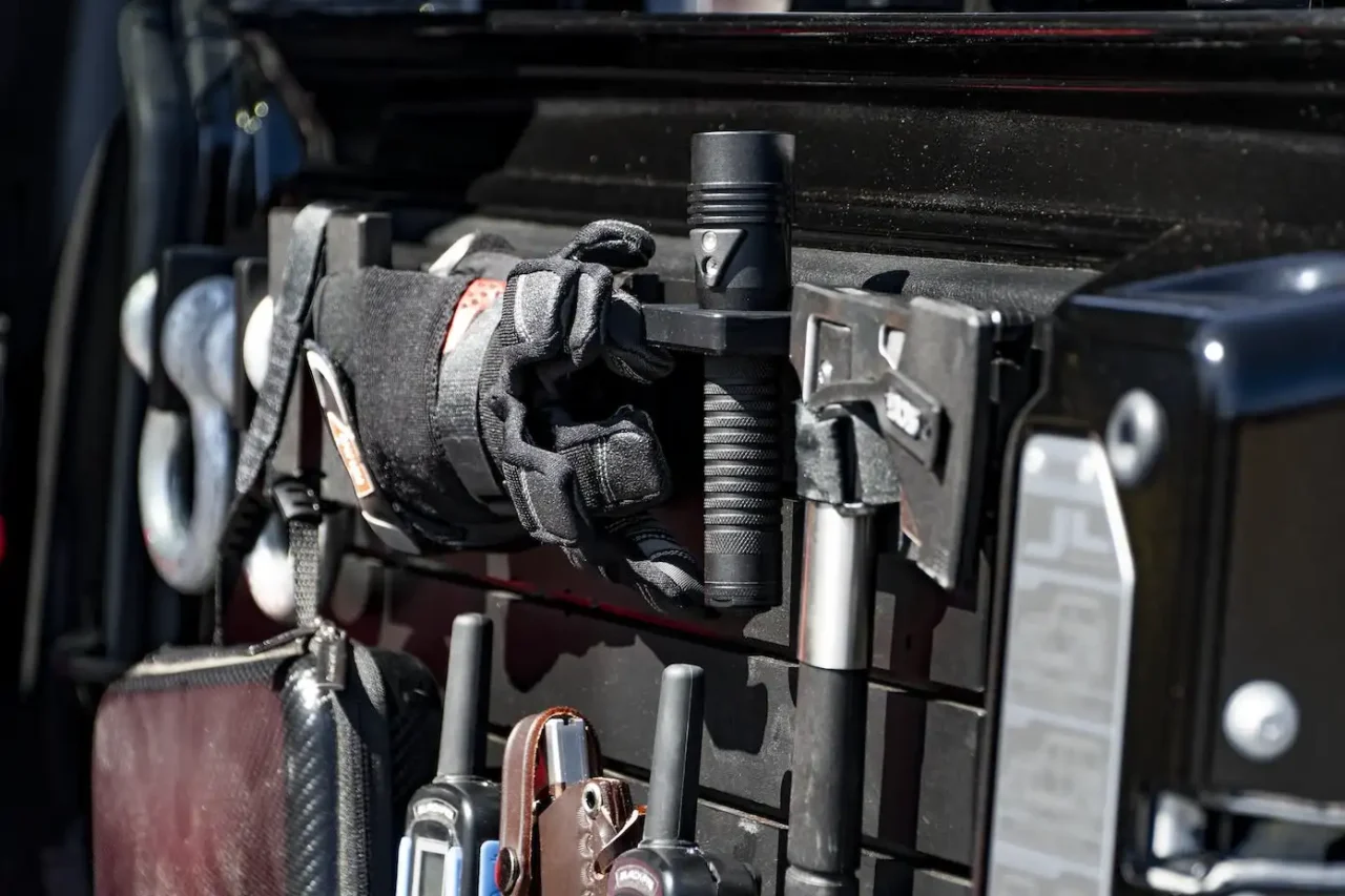 ModWall Flashlight Holder Angled view of the ModWall Flashlight Holder integrated into a professional vehicle storage setup, keeping a flashlight accessible next to an axe and recovery gear.