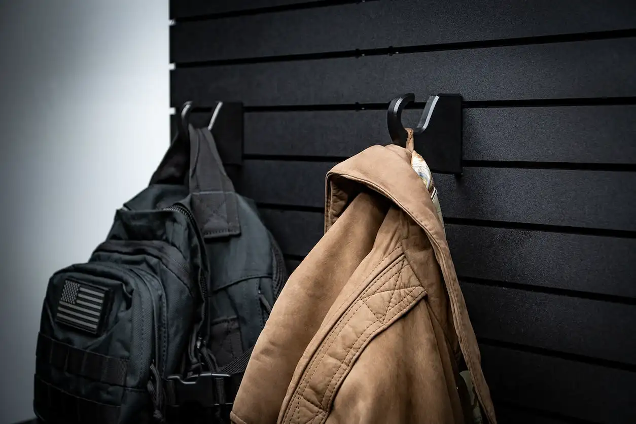 ModWall Hook A tan jacket and a black backpack hanging from multiple ModWall Hooks on a modular storage panel, providing a dedicated staging point for everyday gear.