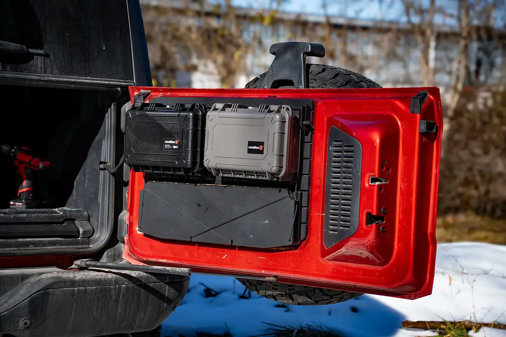 Ford Bronco Tailgate Storage Package An open red Ford Bronco tailgate featuring the modular storage package with two hard-shell gear cases and a folded tailgate table mounted to the black HDPE panel.